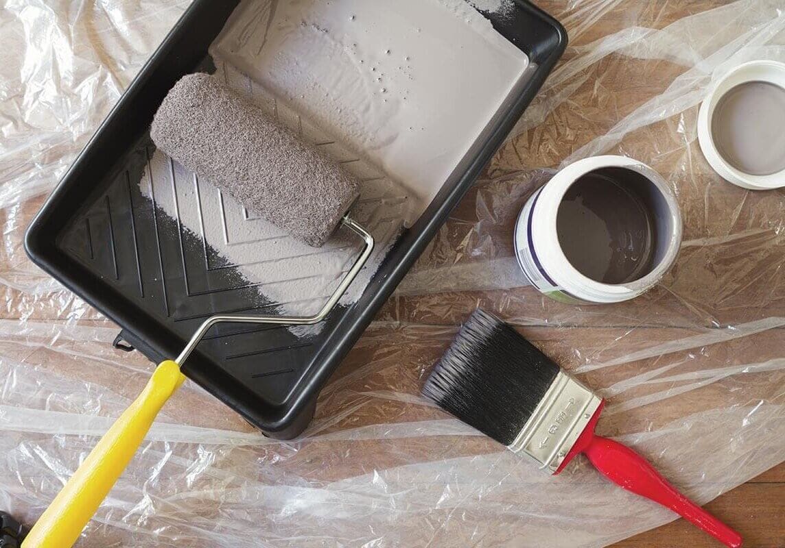 Overhead view of home painting equipment brush, roller, tray and paint pot